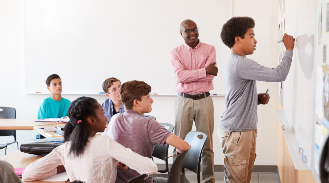 Élève dans une classe écrivant sur un tableau blanc effaçable à sec